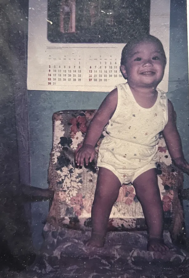 Ian as a baby, standing on a floral chair